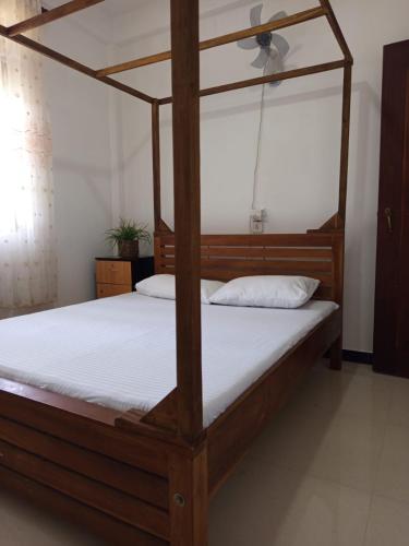 a bedroom with a wooden canopy bed with white sheets at Bright Nest Villa in Matara