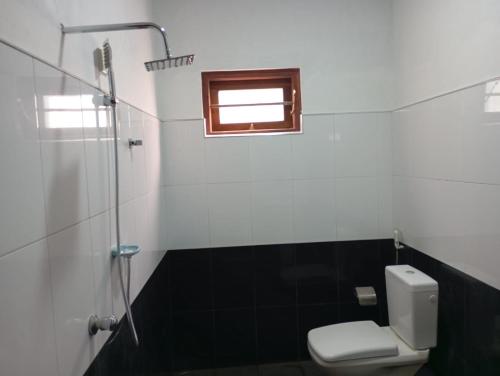 a bathroom with a toilet and a window at Bright Nest Villa in Matara
