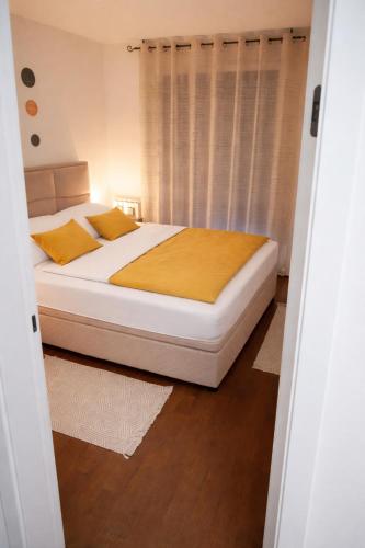 a bedroom with a bed with white sheets and yellow pillows at Muki Park Lake in Tuzla