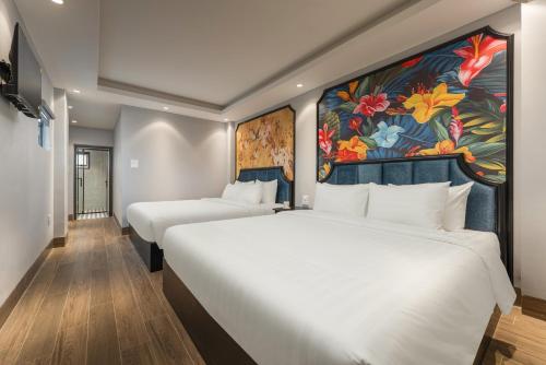 two beds in a hotel room with a painting on the wall at Aurora Hotel & Apartment in Hanoi