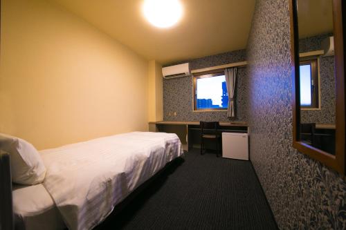 a hotel room with a bed and a desk and a window at HOTEL 910 in Oita