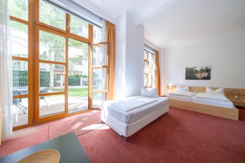 Una sala de estar con dos camas y grandes ventanales. en Hotel 26, en Berlín
