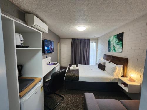 a hotel room with a bed and a desk at Crest Motor Inn in Queanbeyan