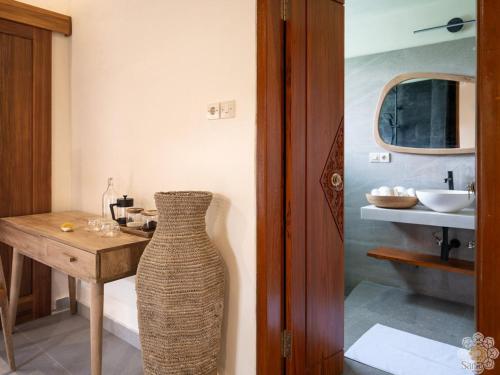 a bathroom with a table and a vase next to a sink at Sananda Aryani in Lovina
