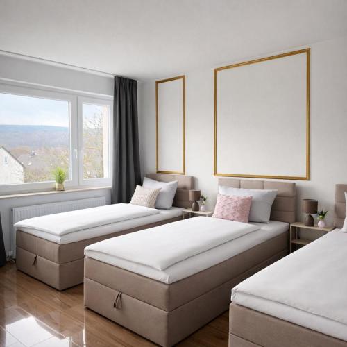 two beds in a room with a large window at Penthouse mit Deisterblick & Balkon in Barsinghausen