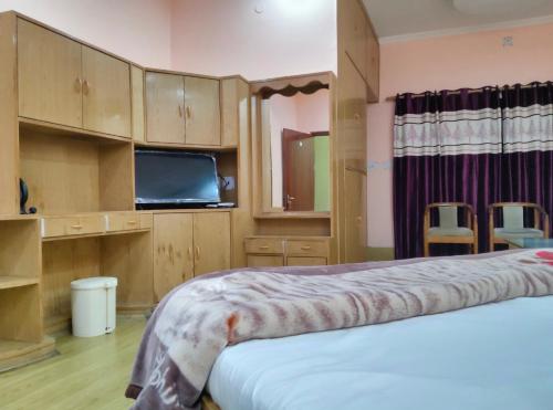 a bedroom with two beds and a tv and cabinets at Hotel Hari mangalam heritage in Tehri-Garhwāl
