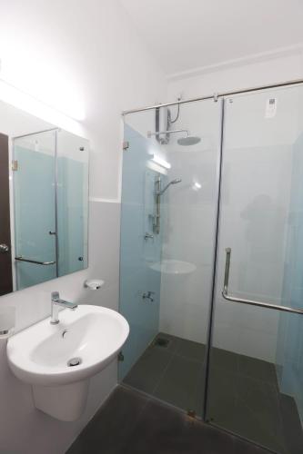 a bathroom with a sink and a glass shower at Santorini Negombo in Negombo