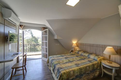 1 dormitorio con 1 cama y balcón en Moinho Itália Hotel, en Campos do Jordão