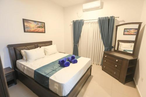 a bedroom with a bed with purple flowers on it at Santorini Negombo in Negombo