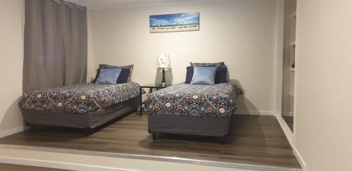 a bedroom with two beds and a chair at Gympie Townhouse in Gympie