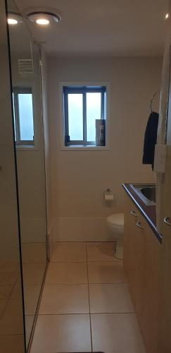 a bathroom with a toilet and a sink and a window at Gympie Townhouse in Gympie