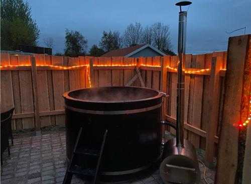 a hot tub in a backyard with a fence at Shelterliv med luksus, nærvær og vildmarksbad in Flemming
