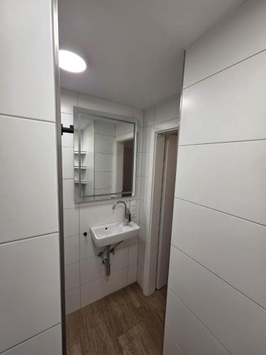 a white bathroom with a sink and a mirror at Maimühle Appartements in Perl