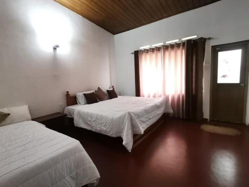 a hotel room with two beds and a window at Felix Holiday Bungalow in Ella