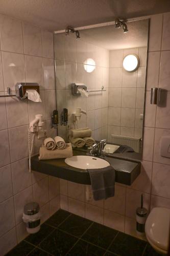 ein Badezimmer mit Waschbecken und Spiegel in der Unterkunft Steingarten Hotel in Wertheim