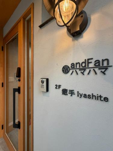 a sign on the side of a building with a light at 宿andFanハマハマ in Meinohama