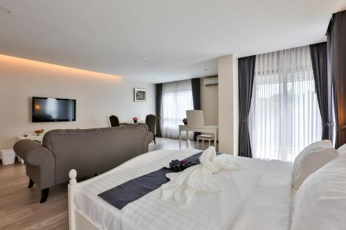 a bedroom with a white bed and a living room at Rung Aroon Hotel By Le Siri in Chiang Mai