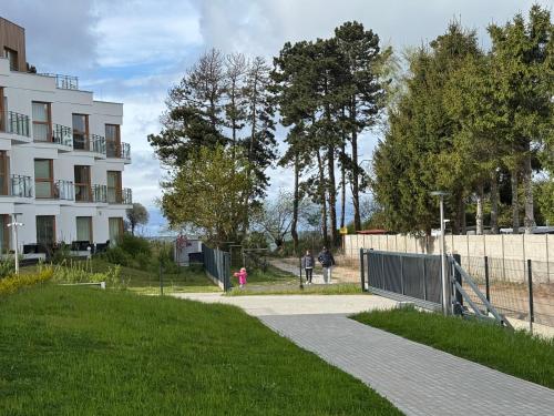 a walkway next to a building with people walking down it at Apartament Mika Let's Sea 73 Tuż przy plaży, klimatyzacja, basen in Gąski