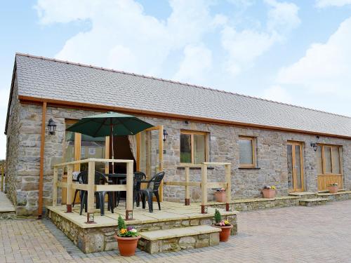 a stone cottage with a table and an umbrella at The Dairy - Op3 in Carmarthen