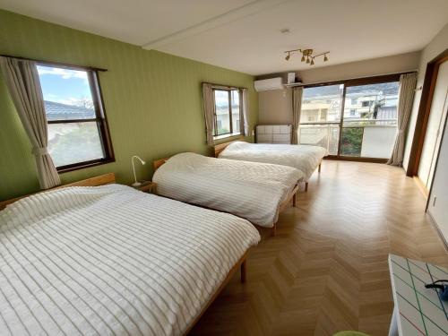 three beds in a room with green walls and windows at Fuka in Beppu -New Open January2026 in Beppu