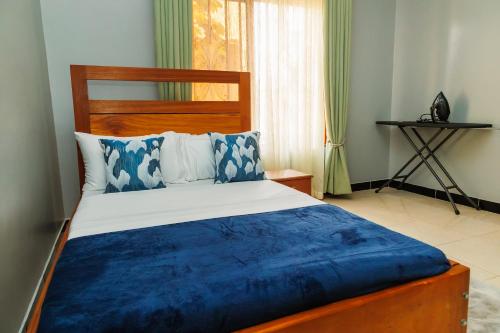a bedroom with a large bed with blue and white pillows at Palm Haven Furnished Apartments in Bweyogerere