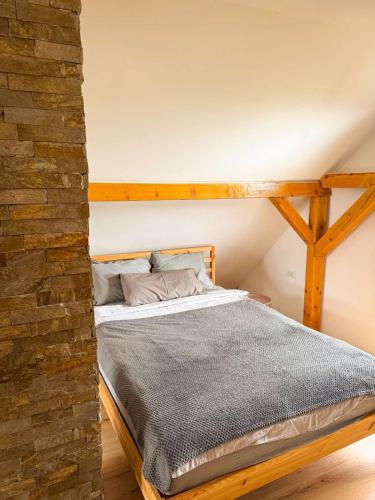 a bed in a room with a brick wall at Vila Xenos Loft Karakter Zlatibor in Zlatibor