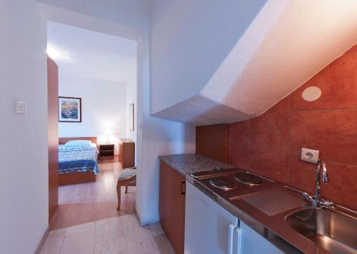 a kitchen with a sink and a room with a bed at Holiday Home Ivanino in Dubrovnik