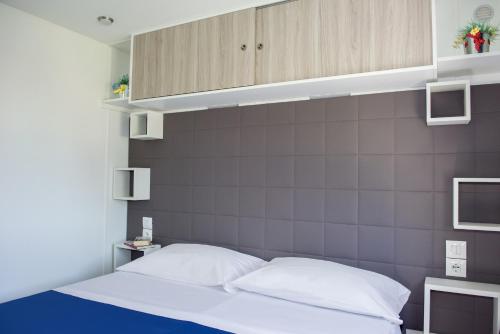 a bedroom with a bed with a gray wall at Camping Village Baia Azzurra in Castiglione della Pescaia