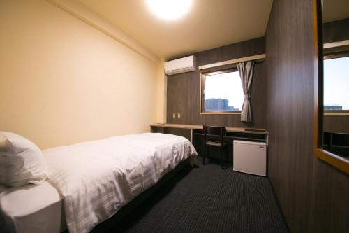 a hotel room with a bed and a desk and a window at HOTEL 910 in Oita
