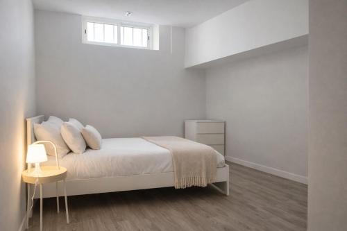 a white bedroom with a bed and a window at Zena Park - Near Lisbon in Odivelas