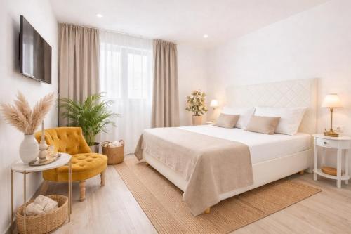 a white bedroom with a bed and a chair at Best Location Beach in Split