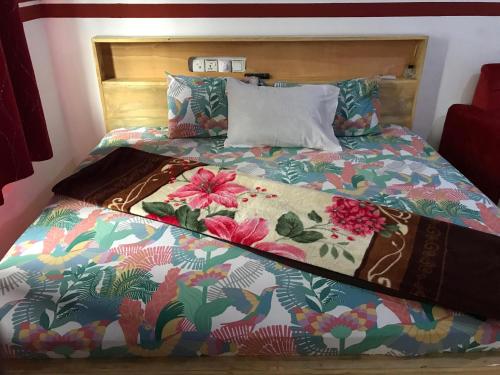 a bed with a colorful comforter and pillows at Alberjah Hotel in Atimpoko