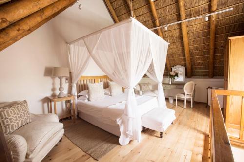 a bedroom with a white bed with a canopy at Klein Waterval Riverside Lodge in Franschhoek