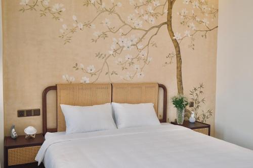 a bedroom with a bed with a tree mural at Mom Villa - Cẩm Thanh in Hiếu Nhơn