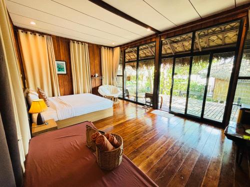 a bedroom with a bed and large glass windows at บ้านริมเลปากประ Banrimlay Pakpra in Phatthalung