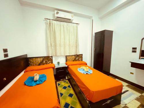 two beds in a room with orange sheets at Bayt Zaina Nile View in Aswan
