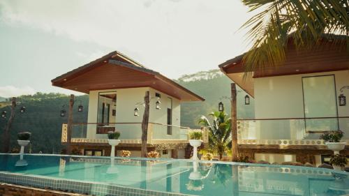 a resort with a swimming pool in front of a building at Homestay Minano in Mock Den