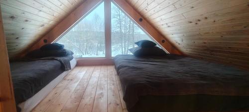 two beds in a room with a large window at Domek w Czarnusze in Augustów