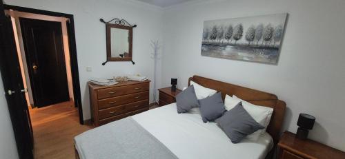 a bedroom with a bed and a dresser and a mirror at Apartment by the Beach Praia da Areia Branca in Lourinhã