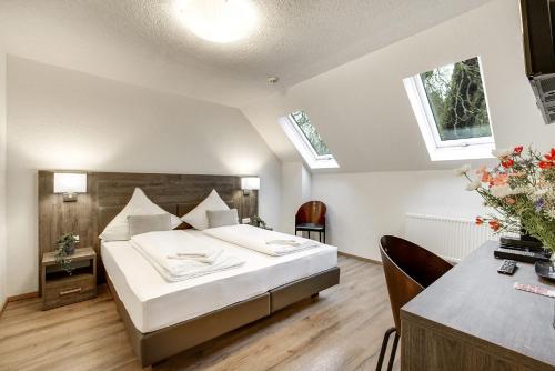 a bedroom with a large white bed and two windows at Hotel Relais Königsberg in Aachen