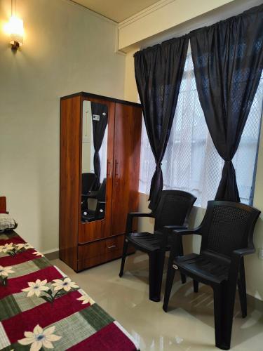 a bedroom with two chairs and a cabinet and windows at Cloud Haven in Lāitlyngkot
