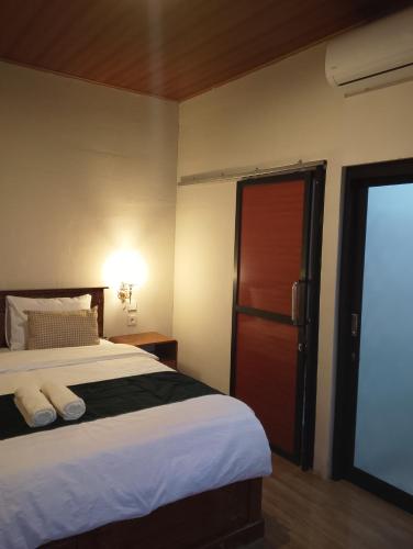a bedroom with a bed and a sliding glass door at Traveling Guest House - Shared Kitchen in Kuta Lombok