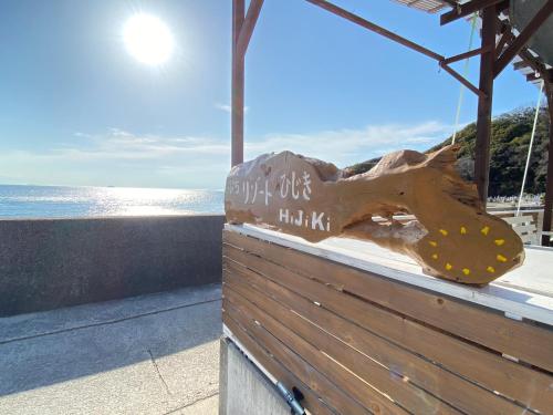 a wooden sign on the side of a building near the ocean at プチリゾート・ひじきwest in Hijiki