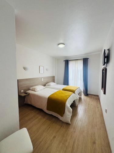 a bedroom with two beds and a window at Residencial Santo António in Santa Cruz