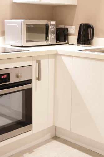 a kitchen with white cabinets and a microwave at Modern 1 Bedroom Apartment Free Parking WiFi Near City Centre in Leeds
