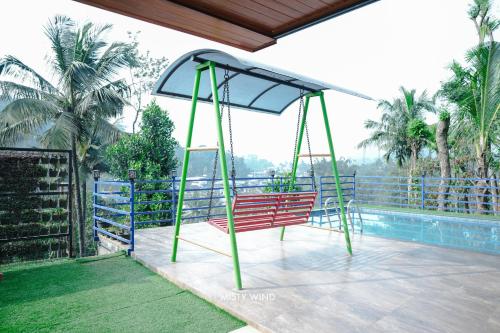 a swing on a balcony with a pool at Vythiri Misty Wind Holiday Homes in Vythiri