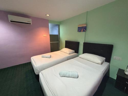 two beds in a room with green and purple walls at Hotel O Peneka Inn in Kota Bharu