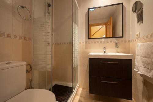 a bathroom with a toilet and a sink and a mirror at Casa modernista in La Zubia
