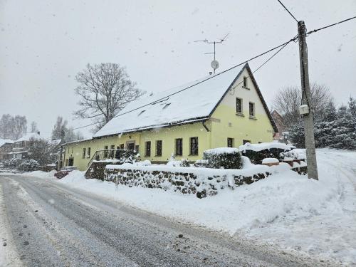 a yellow house on the side of a snow covered road at Apartmán U Davida in Chvaleč