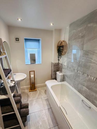 a bathroom with a tub and a sink at Barber House, Hoyland with two allocated parking spaces in Hoyland Nether